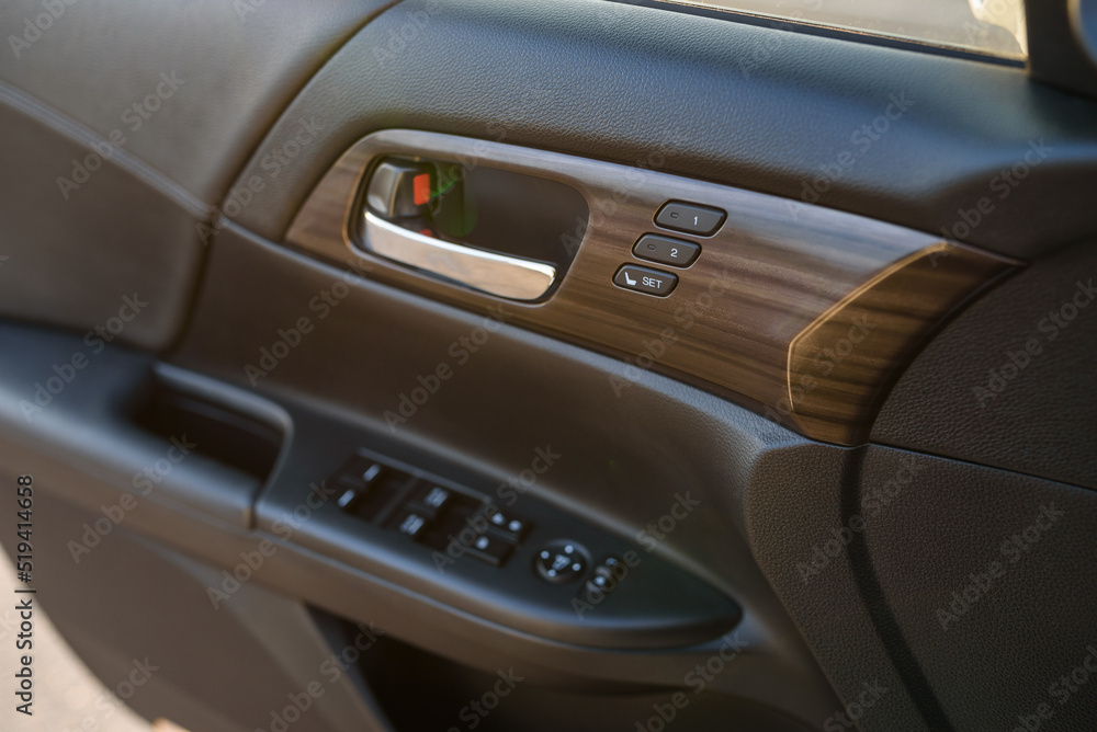 Car door control left panel. Leather new car interior. Car inside door chrome handle. Buttons to adjust driver's seat memory. Lifters control. Blocking the opening and closing of windows and doors.
