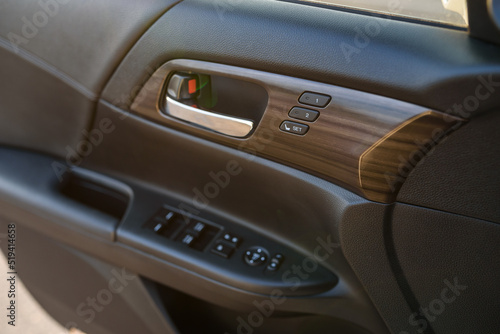 Car door control left panel. Leather new car interior. Car inside door chrome handle. Buttons to adjust driver's seat memory. Lifters control. Blocking the opening and closing of windows and doors. © Serhii