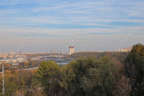 Autumn cityscape at sunset. Panoramic view of the city, bridge, colorful trees, skyscrapers