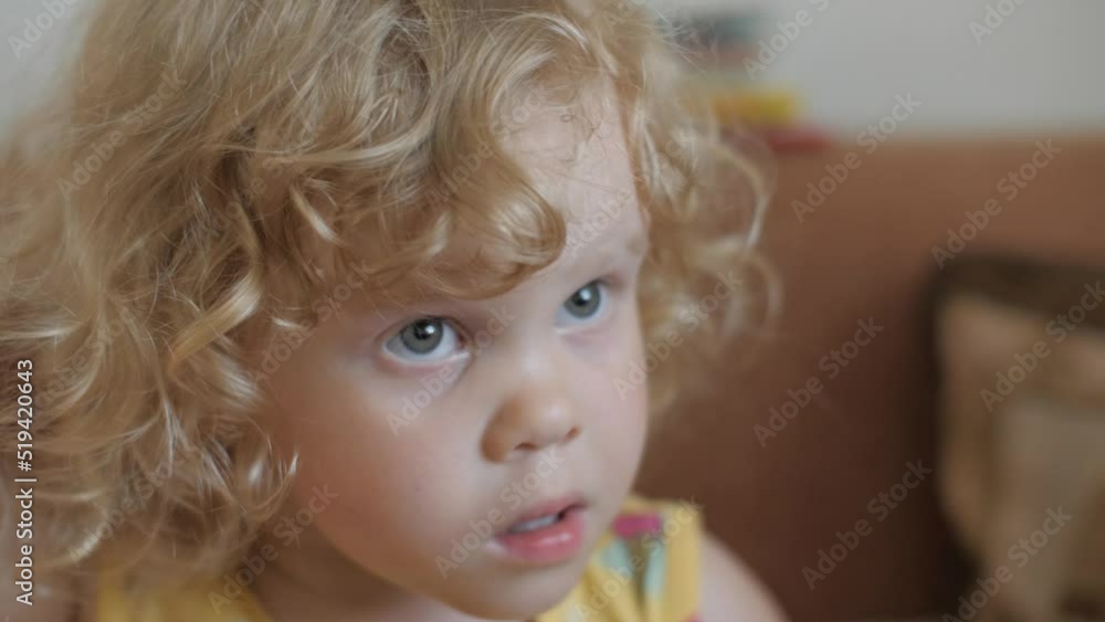Closeup frustrated pensive cute little kid curly blonde boy girl with astonishment face expression Closeup frustrated pensive cute little kid curly blonde boy girl with astonishment face expression