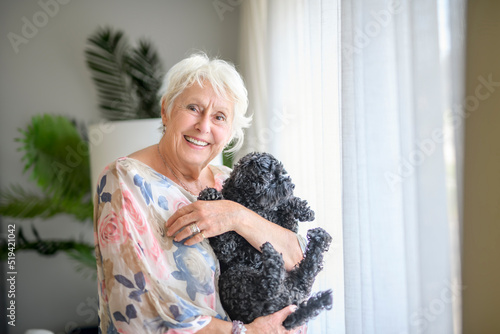 cute senior woman with poodle on the living room photo