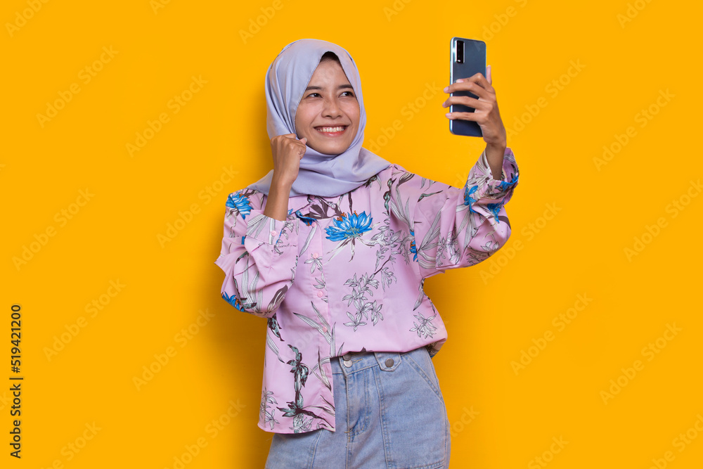 happy young asian beautiful muslim woman using mobile phone isolated on yellow background
happy young asian beautiful muslim woman using mobile phone isolated on yellow background