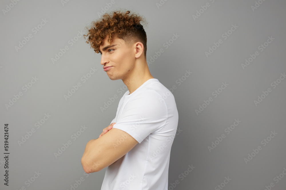 a disappointed, offended young man stands in a white T-shirt on an isolated background, sideways to the camera, pouting in frustration a disappointed, offended young man stands in a white T-shirt on an isolated background, sideways to the camera, pouting in frustration