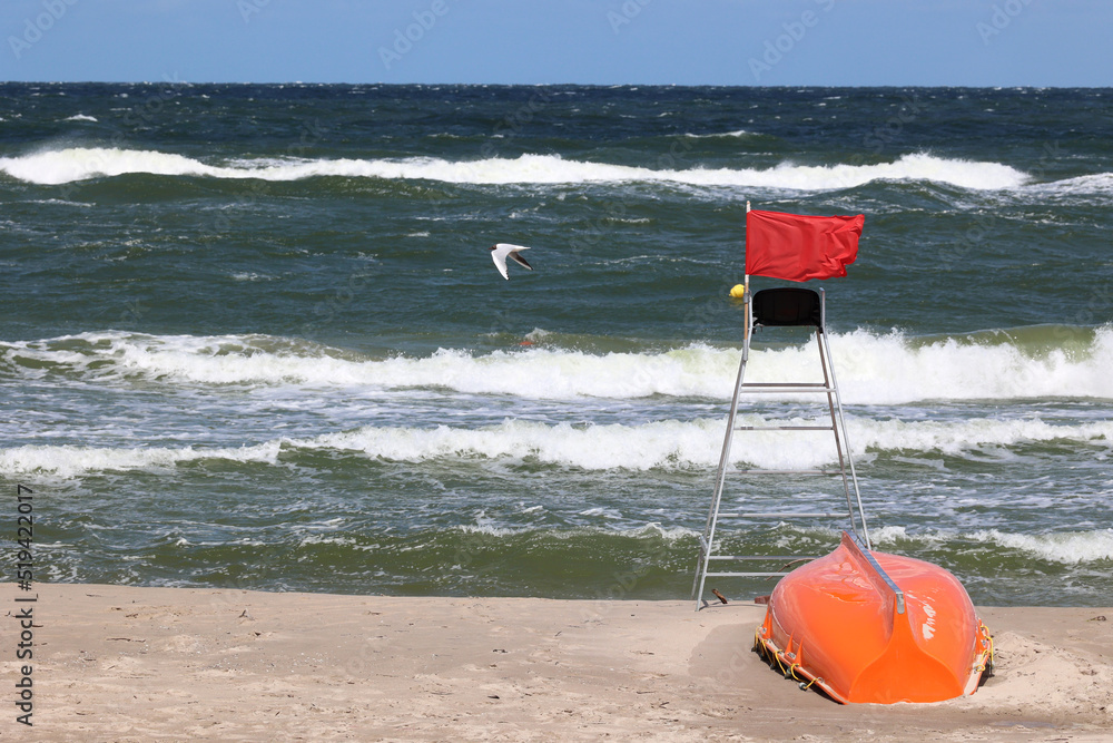 Czerwona flaga na plaży oznacza zakaz kąpieli bo sztorm - obrazy, fototapety, plakaty 
