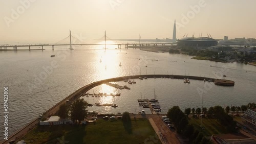 Central yacht club and recreation on the Neva River at sunset, the new cable-stayed bridge and new football stadium on background photo