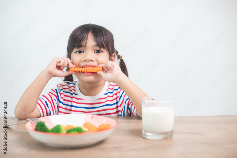 Cute asian child girl eating healthy vegetables and milk for her meal Cute asian child girl eating healthy vegetables and milk for her meal