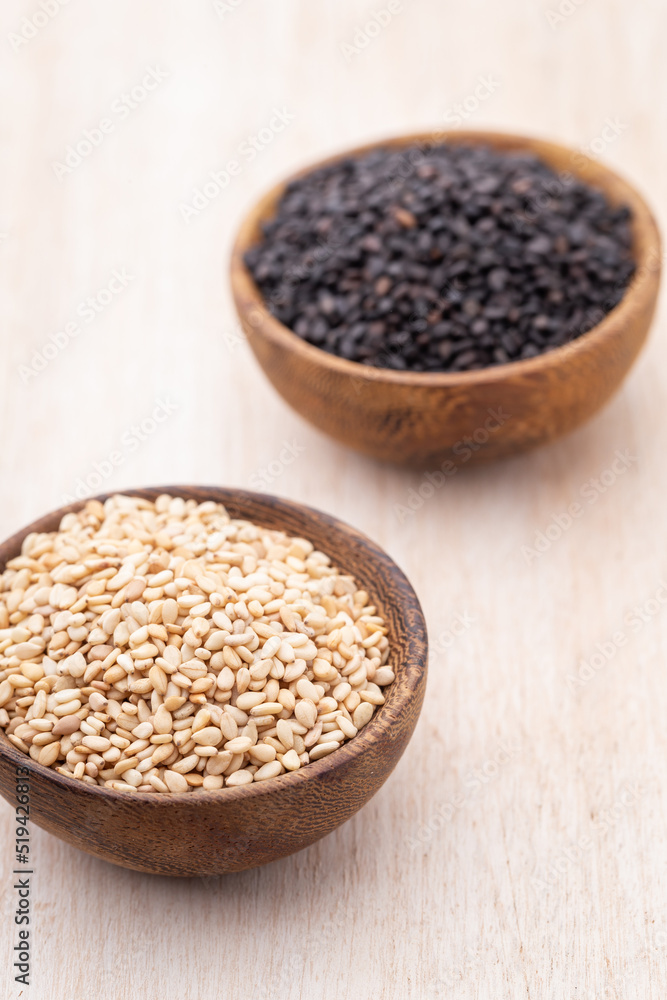 White sesame and black sesame seed on wooden bowl. White sesame and black sesame seed on wooden bowl.