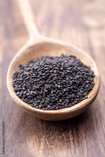 Bio natural black sesame seeds on wooden spoon.