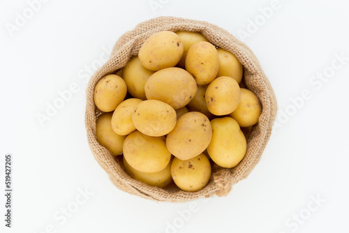 Sack of fresh raw potatoes on wooden background, top view