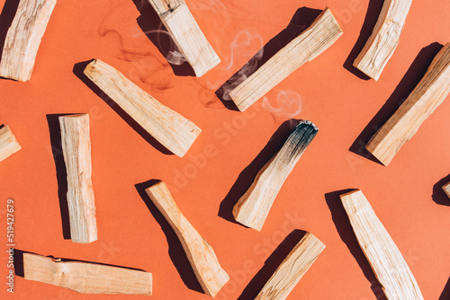 Burning incense - palo santo sticks over orange brown background, Earth tone. Flat lay composition with holy wood sticks for meditation and spiritual practices. Room fumigation ritual. Selective focus