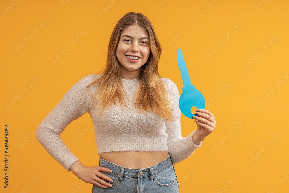 smiling young woman showing big paper key on color background smiling young woman showing big paper key on color background