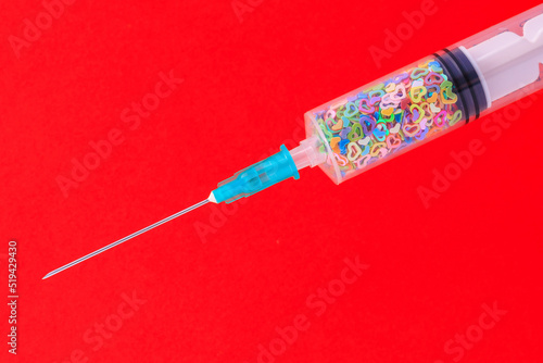 A classic disposable syringe filled with symbolic hearts. Love concept. Background with copy space. Red backdrop photo