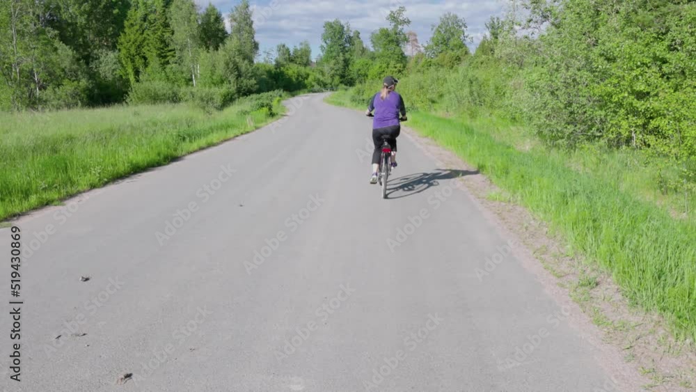 Beautiful view of woman on bicycle moving on small road on beautiful countryside landscape background. Sweden. Beautiful view of woman on bicycle moving on small road on beautiful countryside landscape background. Sweden.