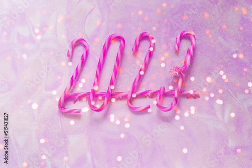 New year 2023 made of christmas candy canes on lavender background with sparkles. New year Color Trends, Attention-grabbing Palettes 2023 year. Creative copy space.