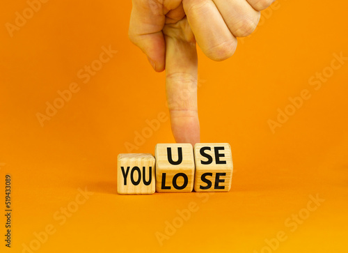 You use or lose it symbol. Concept words You use and You lose on wooden cubes. Businessman hand. Beautiful orange table orange background. Business and you use or lose it concept. Copy space.