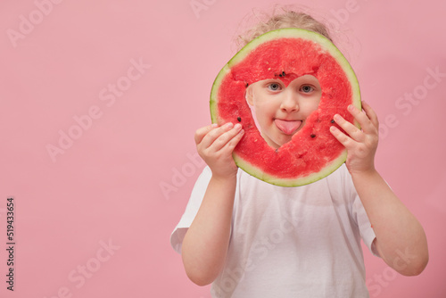 portrait happy young little girl is holding slice of watermelon over colorful pink background