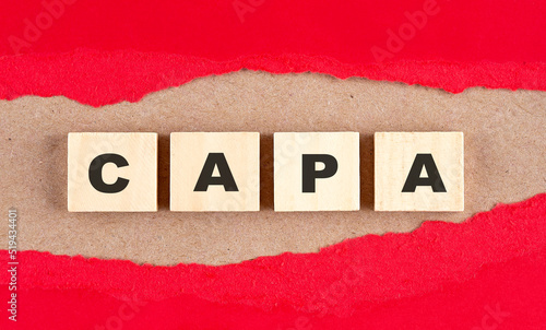 CAPA word on wooden cubes on red torn paper , financial concept background