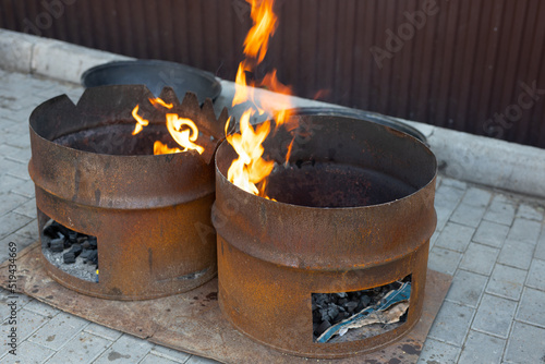 large rusty barrels of coal for roasting on fire