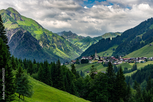 Urlaub im Kleinwalsertal: Wandern auch bei Regen, schlechtem Wetter in Österreich, Bayern - das malerische Hirschegg und Mittelberg von weitem mit Kirchturm und Bergen