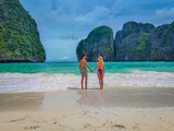 Happy couple of lovers standing together in the Maya bay beach and holding their hands in front of ocean during their honeymoon