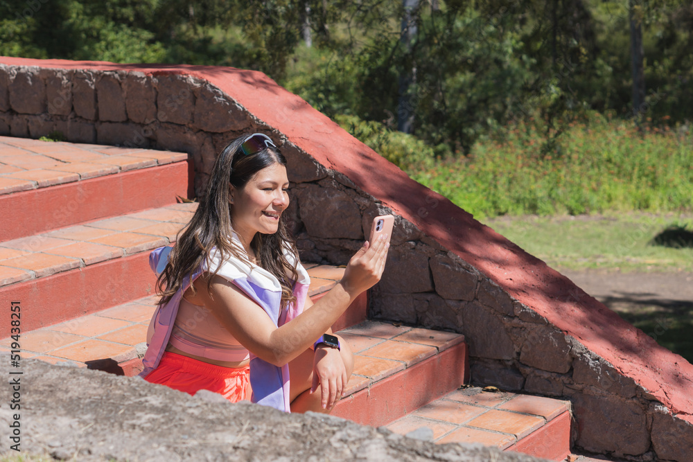 Young woman playing sports outdoors, sharing her day with her cell phone.