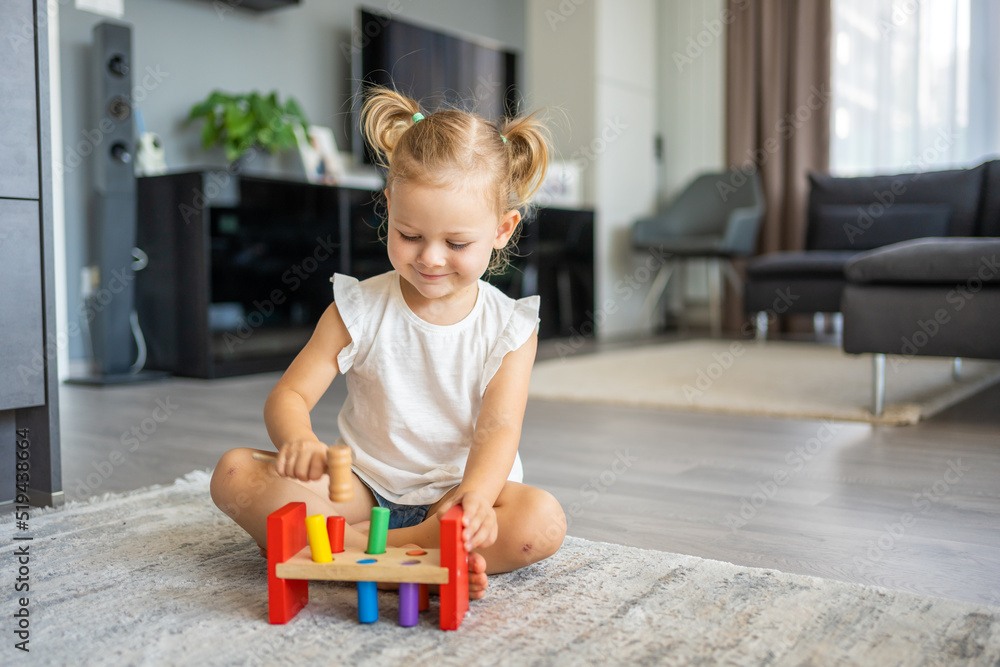 Cute caucasian little girl playing on the floor at home with eco wooden ...