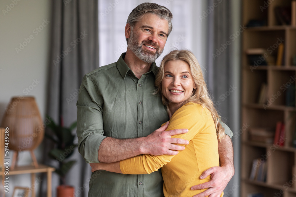 Portrait Of Happy Married Middle Aged Couple Hugging At Home