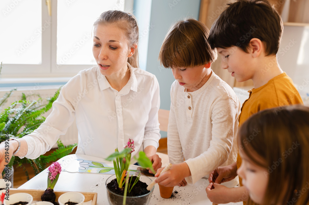 Curious children doing a science project about plants with their teacher. Classroom activities that will get children interested in growing plants Curious children doing a science project about plants with their teacher. Classroom activities that will get children interested in growing plants
