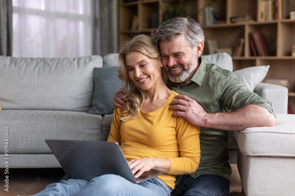 Online Communication. Happy Middle Aged Spouses Using Laptop Computer At Home Online Communication. Happy Middle Aged Spouses Using Laptop Computer At Home