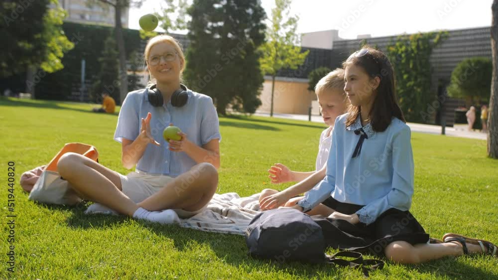 Cheerful and cheerful schoolchildren of different ages are juggling green apples on the lawn of the school yard. School lunch break. Cheerful and cheerful schoolchildren of different ages are juggling green apples on the lawn of the school yard. School lunch break.