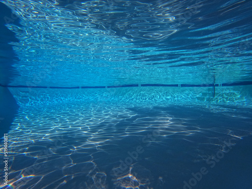 Large clean swimming pool with underwater light patterns and shadows.
