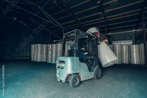 Forklift transports large roll of paper at recycling and toilet paper manufacturing plant.
