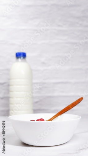 Portrait photo of yoghurt bowl and milk bottle in the background