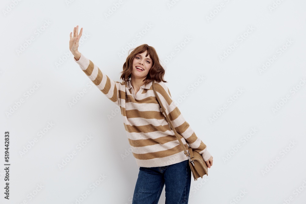 an emotional woman stands on a white background in a striped sweater and a bag on her shoulder , stood sideways on the floor , lowering her arm down and stretching the second forward an emotional woman stands on a white background in a striped sweater and a bag on her shoulder , stood sideways on the floor , lowering her arm down and stretching the second forward