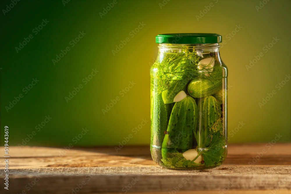 Pickled cucumbers in glass jars on green background. Pickled cucumbers in glass jars on green background.