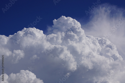 Riesige weiße Quellwolke im heißen Sommer vor azurblauem Himmel. Entwickelt sich daraus eine Gewitterwolke? Ausschnitt, Querformat.