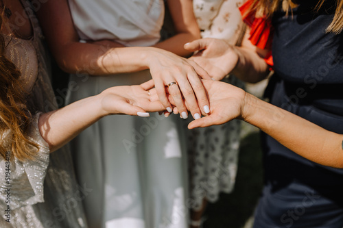 The bridesmaids hold the bride's hand and look at the golden ring on her finger. wedding photography.