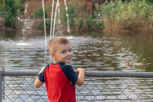 happy five year old boy at the zoo. smiling boy admiring ducks in the pondю concept happy boy having fun in a zoo. 
