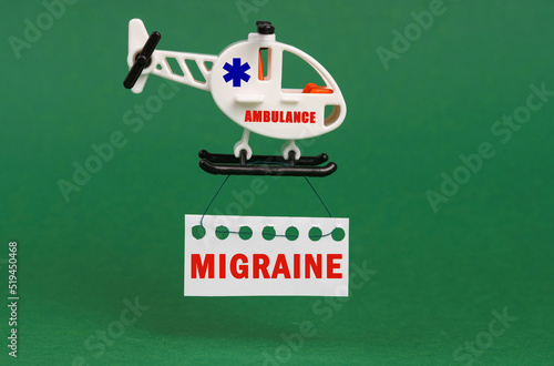 On a green surface, an ambulance helicopter with a sign - MIGRAINE