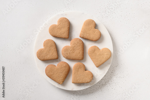 Heart shaped cookies on white marble plate on white background. View from above.