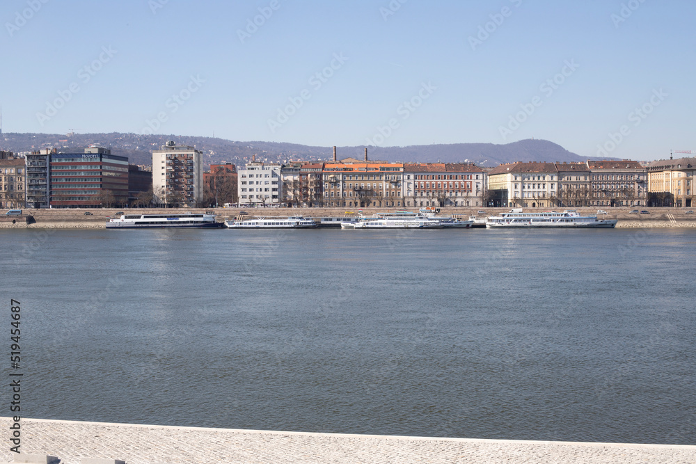 Europe Budapest Danube river. Kravid ashore with ferries and buildings. City on the water
