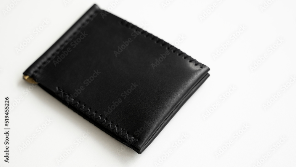 Brown men's money clip handmade leather wallet. Empty money clip wallet with a two pockets for cards lies on a white table. Selective focus, copy space. Brown men's money clip handmade leather wallet. Empty money clip wallet with a two pockets for cards lies on a white table. Selective focus, copy space.