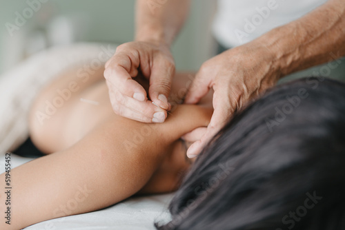 acupuncturist pinches patient's neck to insert acupuncture needle photo