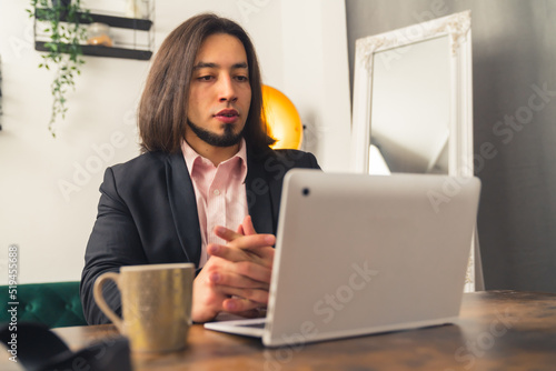 An elegant business person sitting in front of laptop with a glass of coffee on the desk. High quality photo
