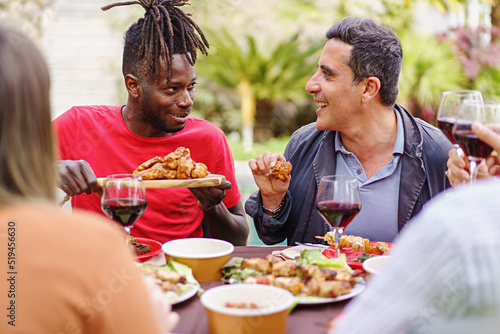 Print op canvas Friends eating chicken wings outdoors- happy people dining and talking together