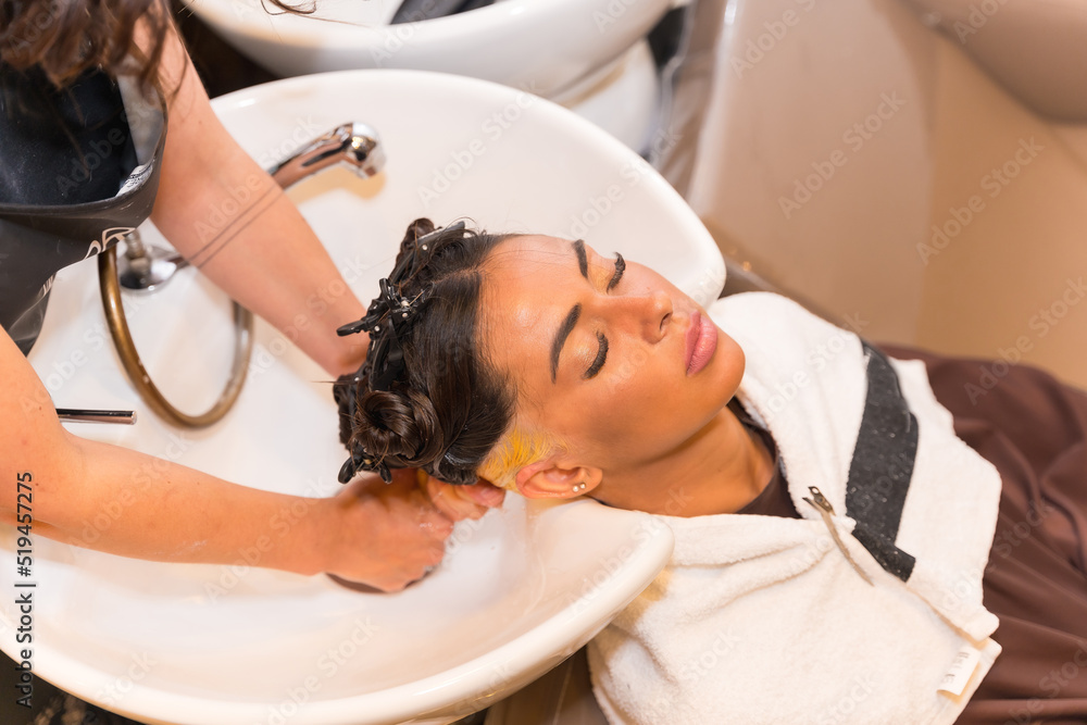 Hairdresser cleaning the hair with hot water and soap to a client in the beauty salon Hairdresser cleaning the hair with hot water and soap to a client in the beauty salon