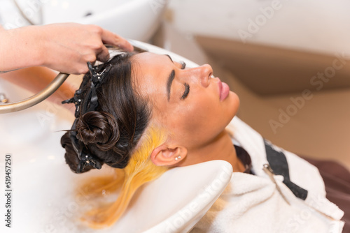 Hairdresser cleaning the hair with hot water and soap to a client