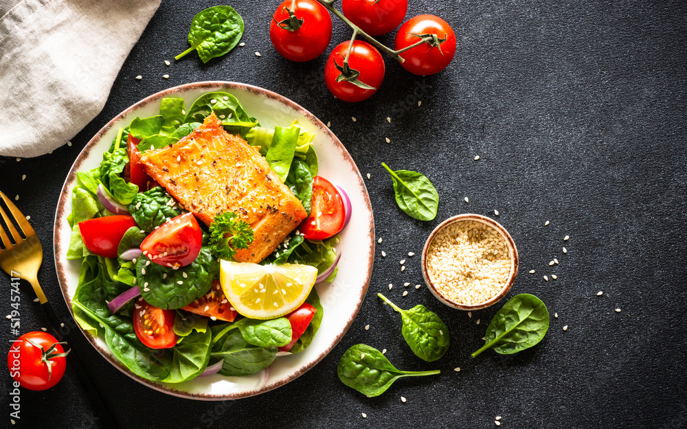 Green salad with vegetables and salmon fillet. Healthy lunch, diet nutrition. Top view on black. Green salad with vegetables and salmon fillet. Healthy lunch, diet nutrition. Top view on black.