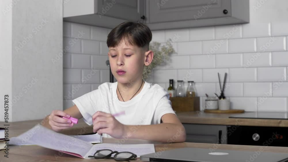 The boy with glasses is finishing his homework. A student folds notebooks and textbooks. Study The boy with glasses is finishing his homework. A student folds notebooks and textbooks. Study