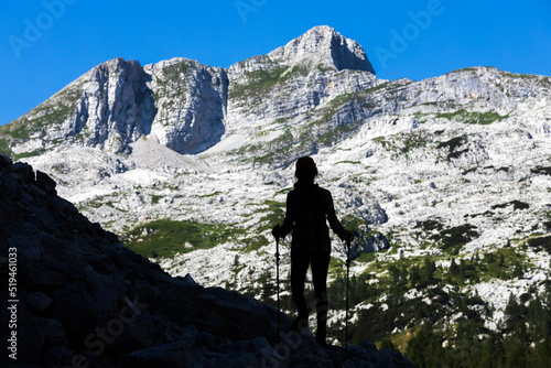 Silhouette of Woman Hiker Standing on the Edge of a Mountain Trail and Admiring The Krn Mountain